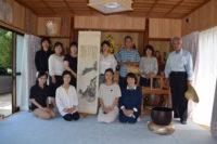 売茶翁が龍律寺7代梁和尚に贈った掛軸の前でスタッフ勢揃い。翁は25年ぶりの龍律寺です